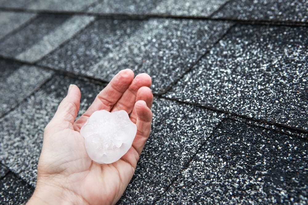 Hail in hand on a rooftop after hailstorm damaged the roof; types of roof damage for professional roofing company in Knoxville, TN