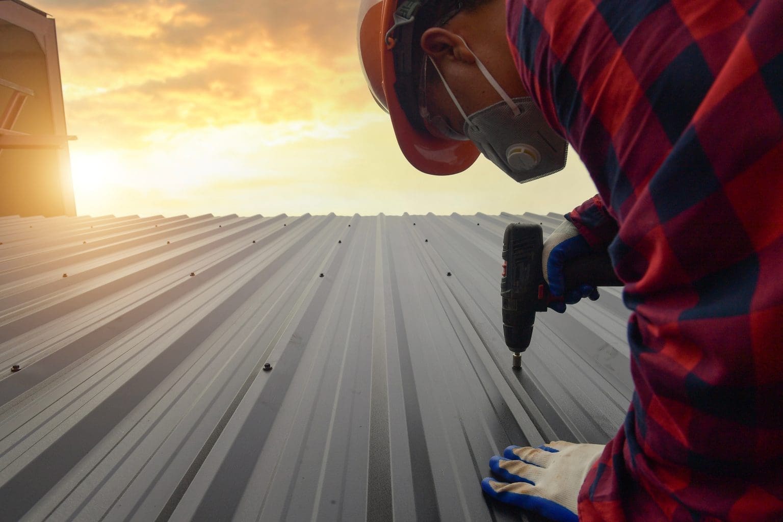 man installing metal roof with drill